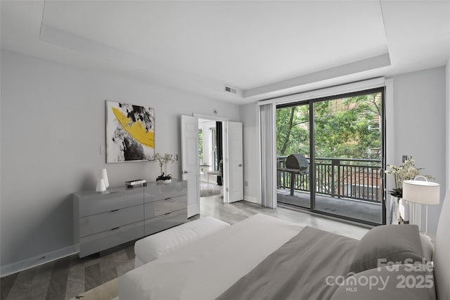 bedroom with access to exterior and a tray ceiling