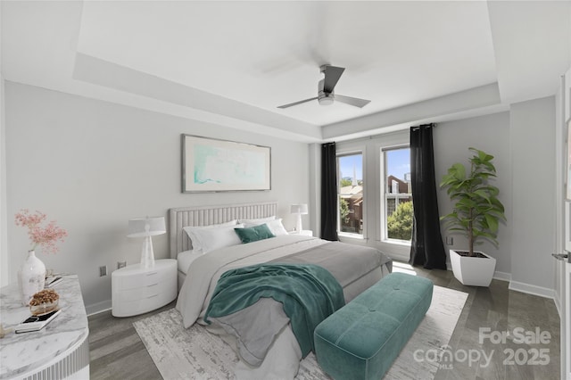 bedroom with a raised ceiling, ceiling fan, and dark hardwood / wood-style floors