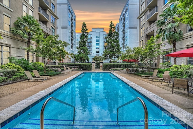 pool at dusk featuring a patio area