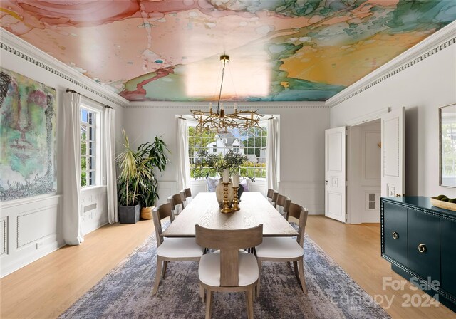 dining room with light wood-type flooring, a wealth of natural light, a chandelier, and crown molding