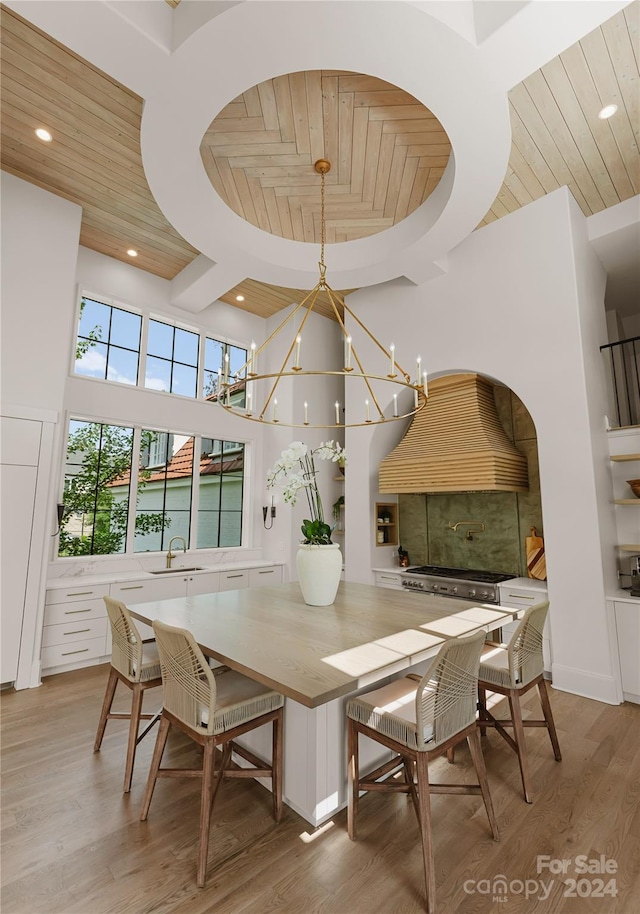 dining space featuring light wood-type flooring, wood ceiling, a chandelier, and sink