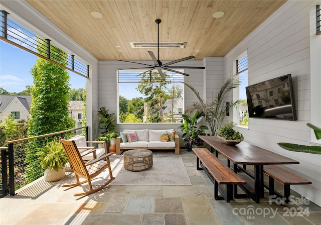 sunroom / solarium featuring wood ceiling, a wealth of natural light, and ceiling fan