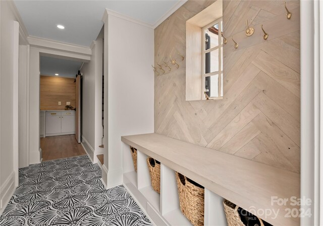 mudroom featuring a barn door and ornamental molding