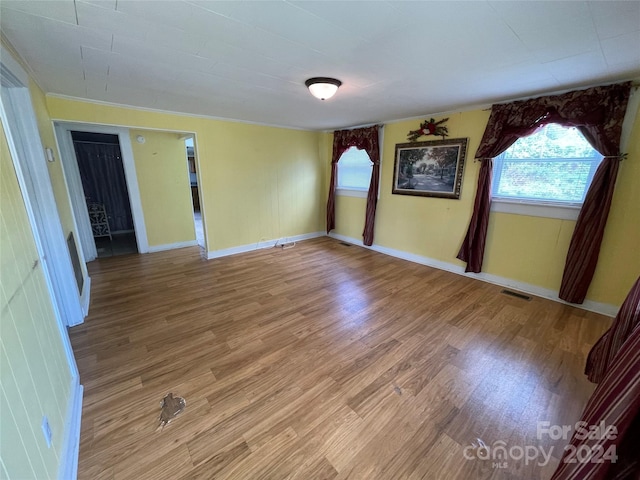 empty room with ornamental molding and hardwood / wood-style floors