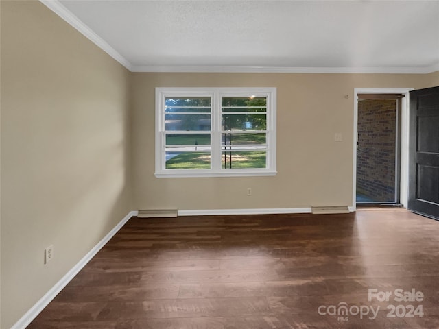 spare room with crown molding, wood finished floors, and baseboards