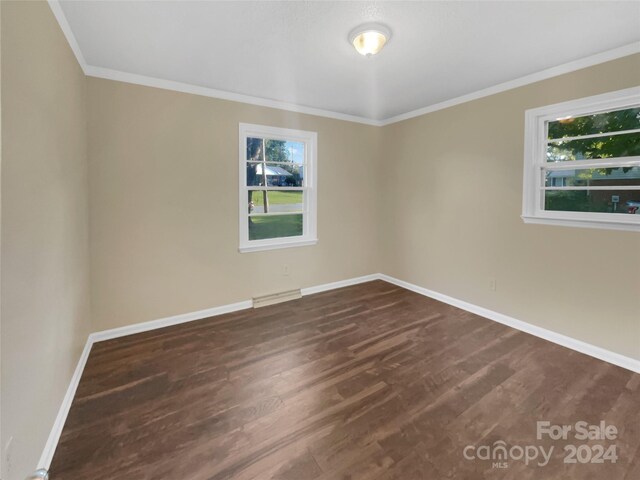 spare room featuring a baseboard heating unit, dark hardwood / wood-style floors, and crown molding