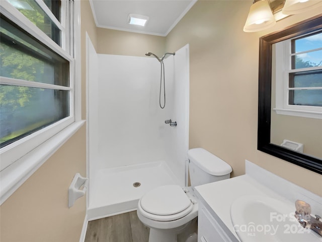 bathroom featuring toilet, hardwood / wood-style floors, ornamental molding, vanity, and a shower