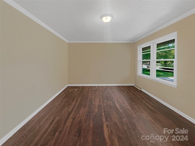 unfurnished room featuring dark wood-type flooring, ornamental molding, and a textured ceiling