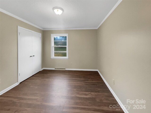 spare room featuring crown molding and dark hardwood / wood-style flooring