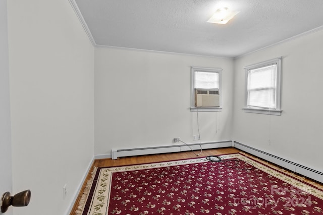 unfurnished room with crown molding, baseboard heating, and light wood-type flooring