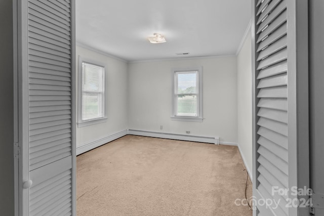 carpeted spare room featuring ornamental molding, baseboard heating, and plenty of natural light