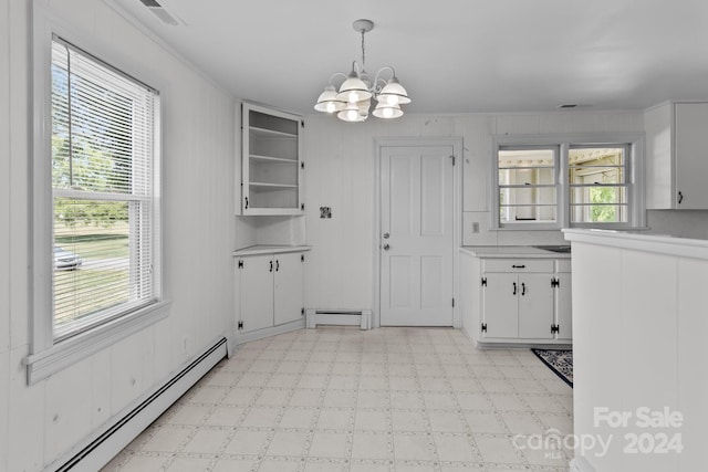 unfurnished dining area with ornamental molding, baseboard heating, and a chandelier