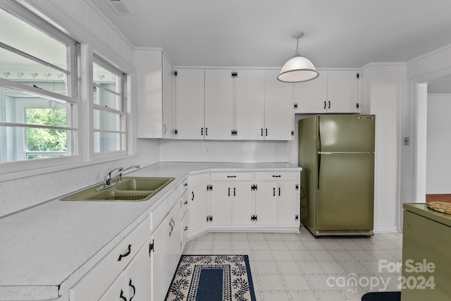 kitchen featuring stainless steel fridge, white cabinetry, sink, and hanging light fixtures