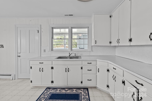 kitchen with baseboard heating, ornamental molding, white cabinetry, and sink