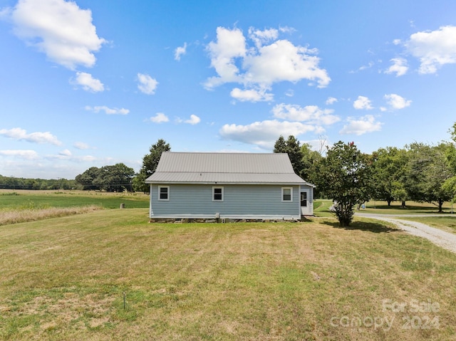 view of home's exterior with a lawn and a rural view