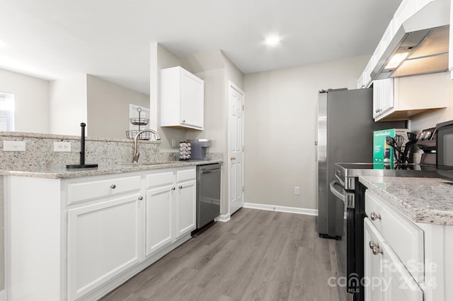 kitchen with light wood-type flooring, white cabinetry, sink, light stone countertops, and appliances with stainless steel finishes