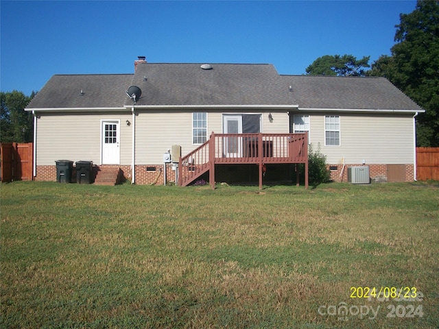 rear view of property with a lawn, central AC unit, and a wooden deck