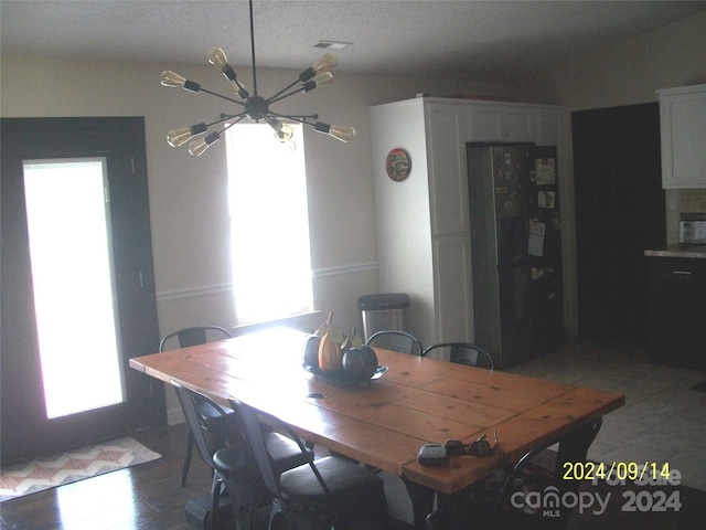 dining room with hardwood / wood-style flooring, plenty of natural light, a textured ceiling, and an inviting chandelier