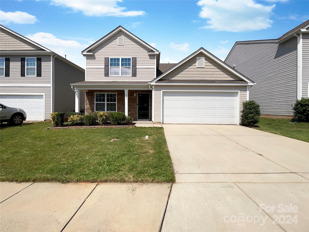 traditional-style house featuring a garage, concrete driveway, brick siding, and a front yard