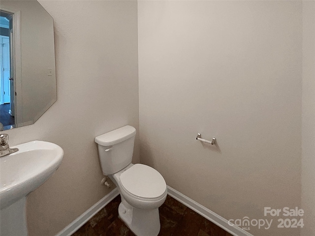 bathroom featuring baseboards, a sink, and toilet