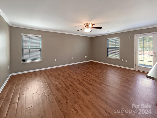 empty room featuring dark wood-style floors, baseboards, and ornamental molding