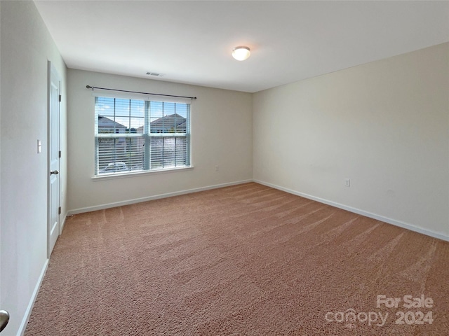 empty room with carpet floors, visible vents, and baseboards