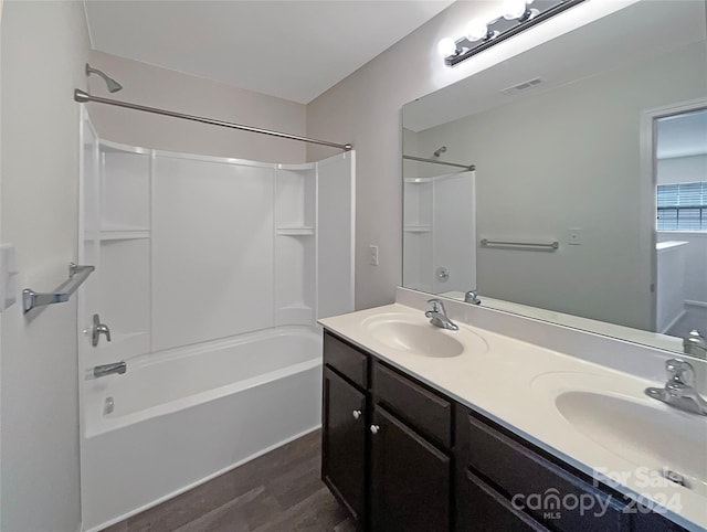 full bathroom with wood finished floors, a sink, bathing tub / shower combination, and double vanity