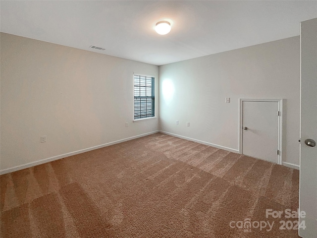 unfurnished room featuring carpet, visible vents, and baseboards