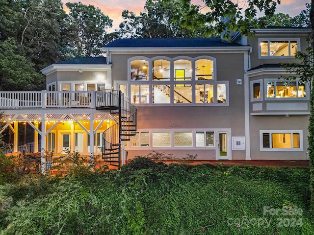 back house at dusk featuring a deck