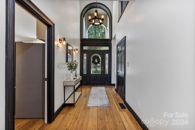 foyer entrance with an inviting chandelier, light wood-type flooring, and a high ceiling