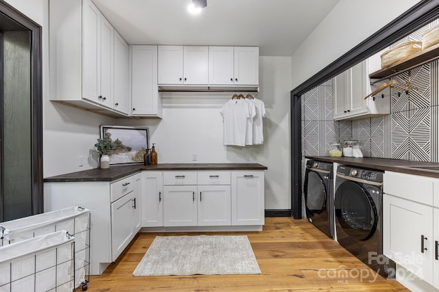 kitchen featuring white cabinets, light wood-type flooring, and washer and dryer