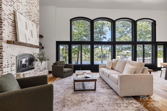 living room with a healthy amount of sunlight, a water view, hardwood / wood-style flooring, and a fireplace