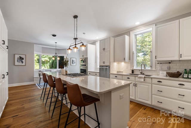 kitchen featuring white cabinetry, a center island, sink, and plenty of natural light