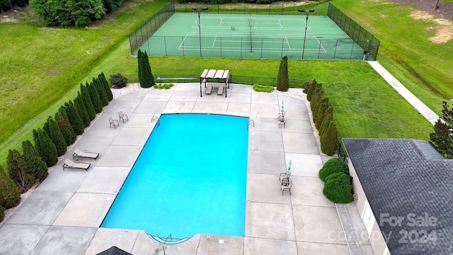 view of pool featuring a lawn, tennis court, and a patio