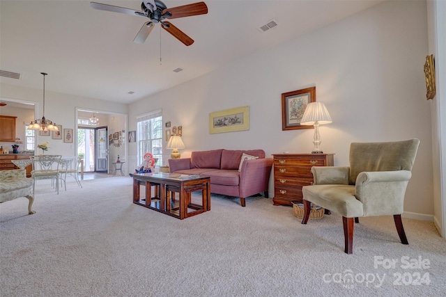 carpeted living room featuring ceiling fan with notable chandelier