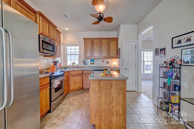 kitchen featuring plenty of natural light, a kitchen island, stainless steel appliances, and ceiling fan