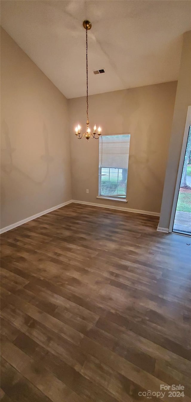 unfurnished dining area featuring dark wood finished floors, a notable chandelier, baseboards, and visible vents