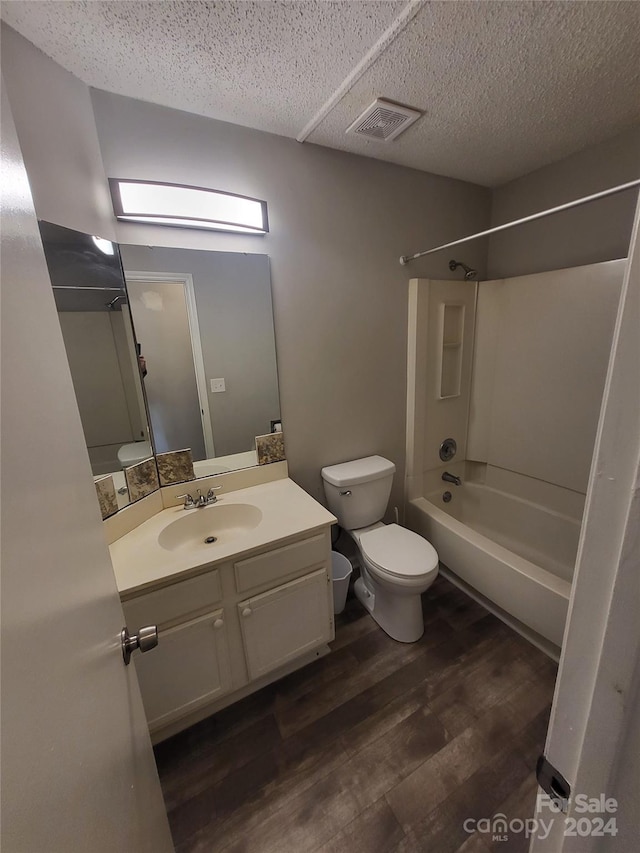 full bath featuring visible vents, shower / washtub combination, toilet, wood finished floors, and vanity