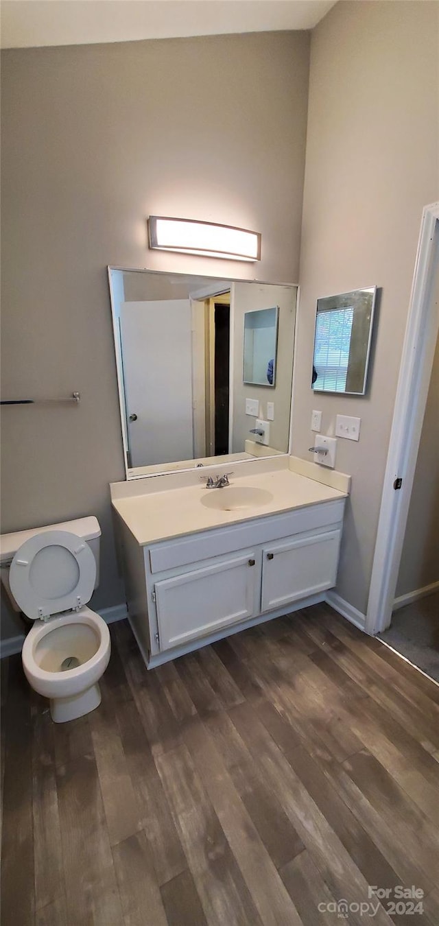 bathroom featuring vanity, toilet, wood finished floors, and baseboards