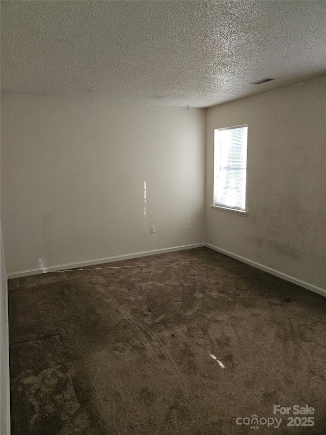 empty room featuring a textured ceiling and dark carpet