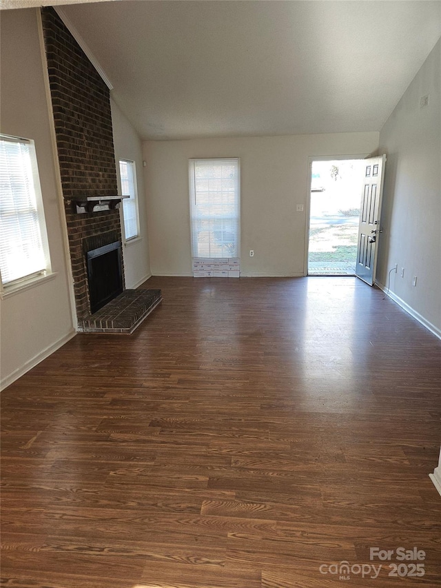 unfurnished living room with vaulted ceiling, a brick fireplace, and dark hardwood / wood-style flooring