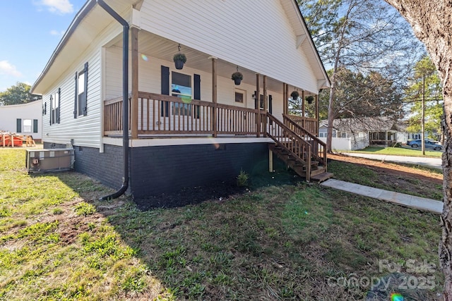 view of front of house featuring a front yard, a porch, and cooling unit