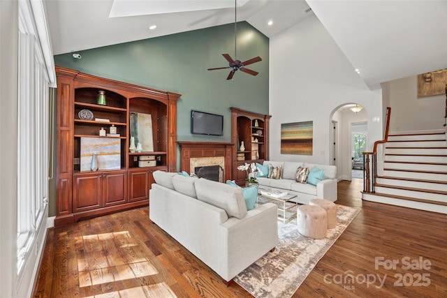 living room with ceiling fan, a high end fireplace, dark hardwood / wood-style floors, and high vaulted ceiling