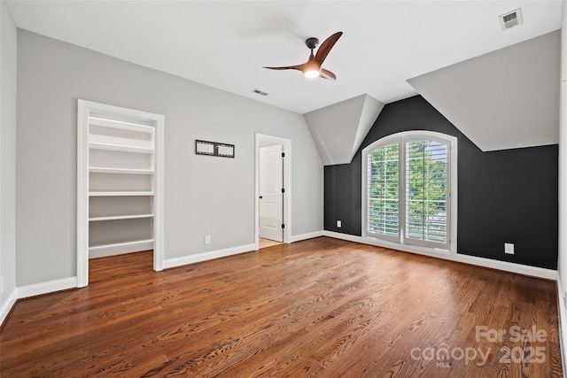 unfurnished bedroom featuring hardwood / wood-style flooring, vaulted ceiling, a spacious closet, and ceiling fan