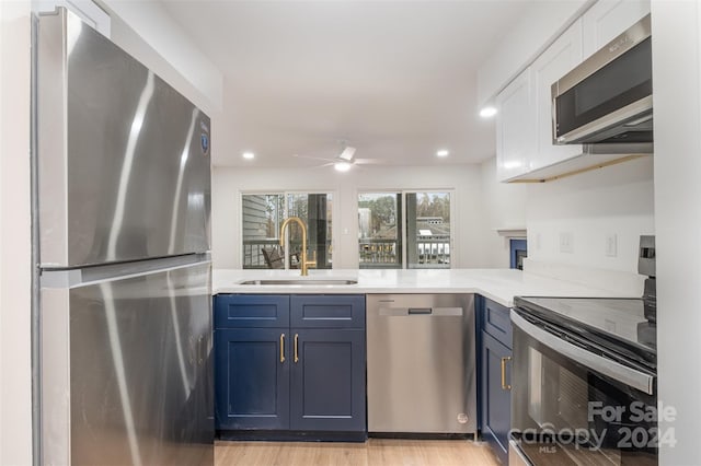 kitchen with blue cabinetry, sink, stainless steel appliances, and light wood-type flooring