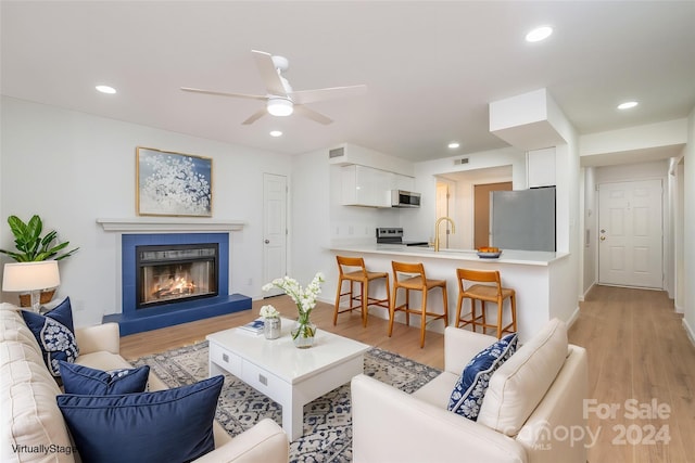 living room with ceiling fan, sink, and light hardwood / wood-style flooring