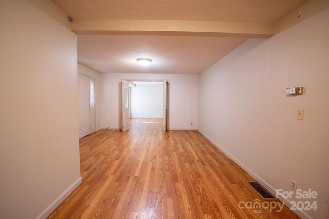 unfurnished room with a textured ceiling and light hardwood / wood-style flooring