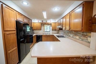 kitchen with black appliances, tasteful backsplash, kitchen peninsula, and sink