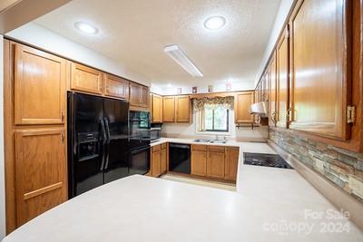 kitchen with black appliances, sink, range hood, and tasteful backsplash