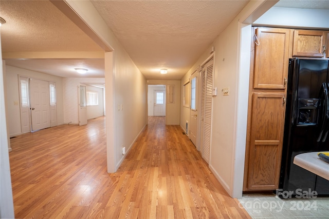 hall with a textured ceiling and light hardwood / wood-style flooring